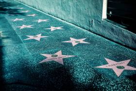 stereotypes in hollywood pink stars on gray tiled street sidewalk