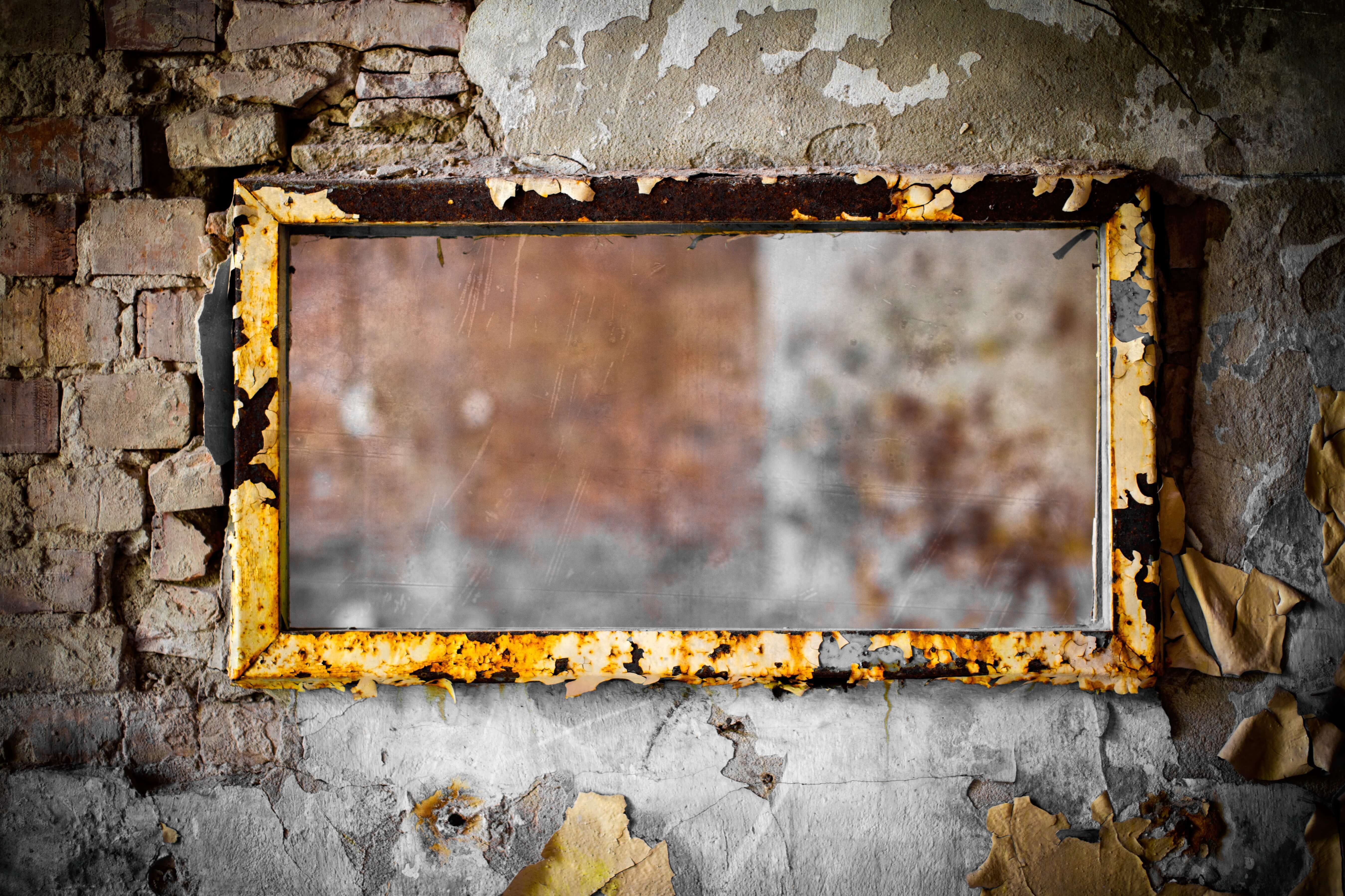 An old mirror on a cracked wall representing the weight of old stories