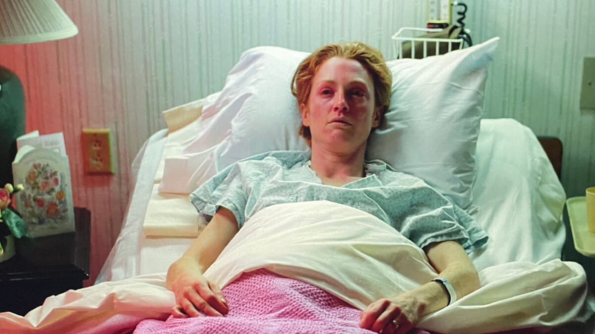 Image of a woman reclined in a hospital bed, face drained of color.